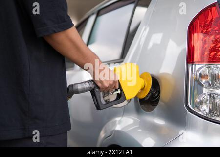 Closeup image of hand holding nozzle fuel fill oil into car tank at gas station. Stock Photo