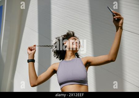 Portrait of sporty smiling young woman after running making selfie outdoors  Stock Photo