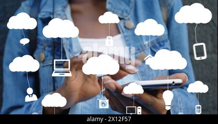 Image of clouds with electronic devices over african american woman using smartphone Stock Photo