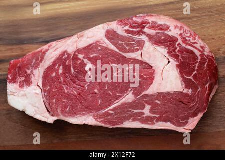 A raw marbled ribeye steak on a cutting board Stock Photo