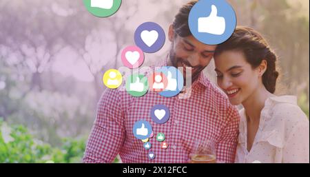 Image of media icons over happy biracial couple using smartphone Stock Photo
