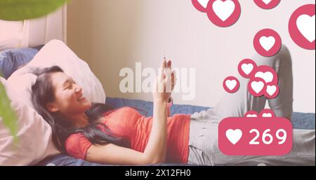 Image of media icons over happy asian woman using smartphone Stock Photo