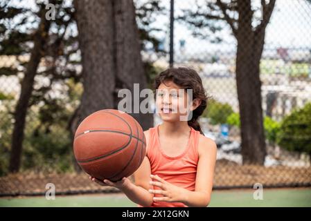 Young hispanic girl holding basketball on court in San Francisco Stock Photo