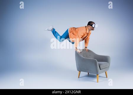 A man in an orange shirt showcases a mesmerizing trick on a chair, creating a captivating and artistic display. Stock Photo