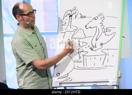 Hanover, Germany. 15th Apr, 2024. Children's book author Ingo Siegner shows how he invented his book character Dragon Coconut in 2000 at a reading for primary school children at the Künstlerhaus Hannover. To mark the 70th anniversary of the Friedrich-Bödecker-Kreis Niedersachsen (FBK), 70 readings by authors for nurseries and schools in Lower Saxony are taking place. Children's book author Ingo Siegner read from his Dragon Coconut books. Credit: Julian Stratenschulte/dpa/Alamy Live News Stock Photo