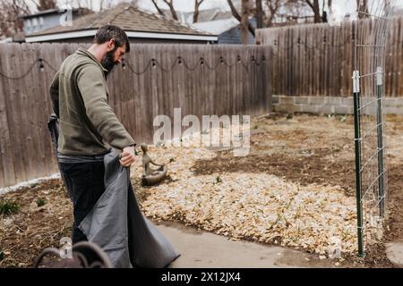 Man covers plants with bedsheet to protect them from snowstorm Stock Photo