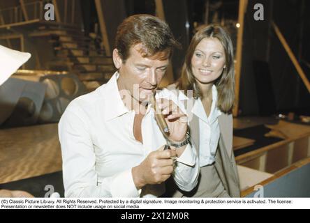 Sir Roger Moore , 1927-2017 during a media event in connection with the recording of the feature film The man with the golden gun at Pinewood studios. Roger Moore is known for his role as agent James Bond, playing the character in seven feature films.  Actress Maud Adams plays the role of Andrea Anders in the movie. 1974. Stock Photo