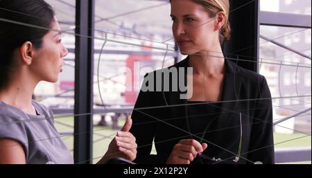 Image of tunnel in seamless pattern over two diverse businesswomen discussing at office Stock Photo
