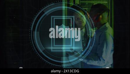 Image of shield icon over african american male and female engineer using laptop at server room Stock Photo