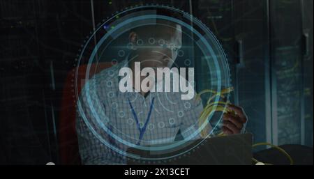 Image of fingerprint scanner over african american male engineer holding a cable at server room Stock Photo