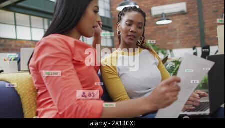 Image of multiple notification bars over diverse female coworkers discussing reports Stock Photo