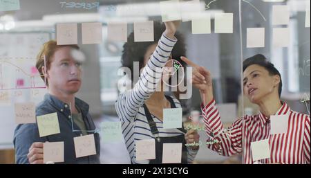 Image of graph, globe and computer language over diverse female coworkers discussing strategy Stock Photo