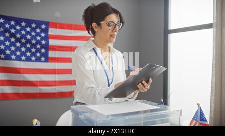 A mature hispanic woman indoors in a professional setting with an american flag at the background, holding a clipboard. Stock Photo