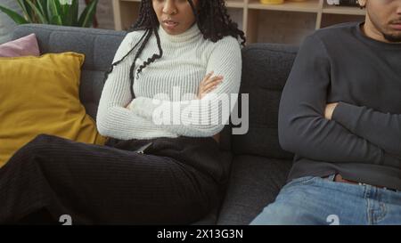 A man and woman in a disagreement sitting apart on a sofa showing tension and unhappiness in a home setting. Stock Photo
