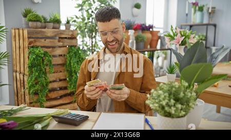 A hispanic man counts money in a vibrant indoor flower shop, surrounded by green plants and daylight. Stock Photo