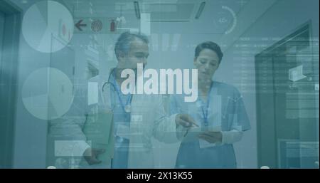 Image of graphs and data over diverse female and male doctors walking in hospital Stock Photo