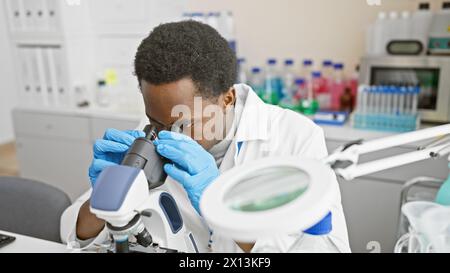 African male scientist using microscope in laboratory Stock Photo