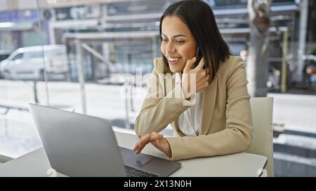 Smiling woman using laptop in modern office environment, portraying productivity and contemporary business lifestyle. Stock Photo