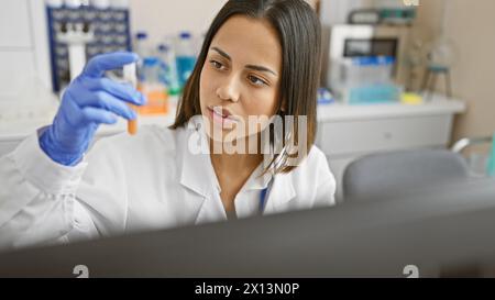 Hispanic woman scientist analyzing a sample in a laboratory setting, wearing a lab coat and gloves. Stock Photo
