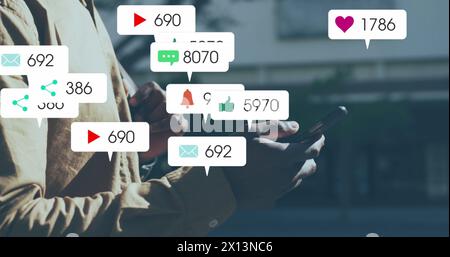 Image of multiple social media icons over mid section of a man using smartphone outdoors Stock Photo