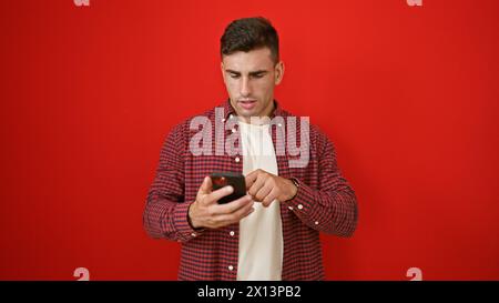 Young hispanic man using smartphone over isolated red background Stock Photo
