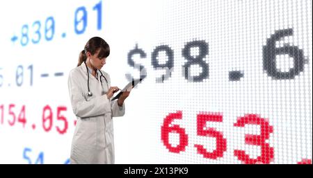 Image of financial data and graphs over caucasian female doctor Stock Photo