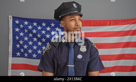 African american policeman with 'voted' sticker, standing in uniform in front of the us flag, representing law, order, and civic duty. Stock Photo