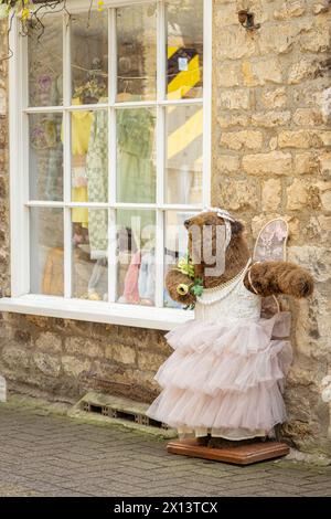 A big brown bear wearing a dress makes for an eye catching promotional tool outside an independent clothes shop in The Cotswolds. Bear in a dress. Stock Photo