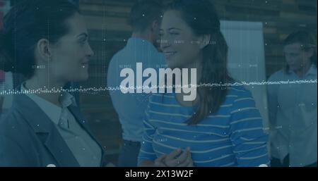 Image of statistical data processing over two diverse businesswomen discussing at office Stock Photo