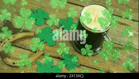 Image of st patrick's day shamrock and glass of beer on wooden background Stock Photo