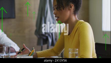 Image of arrows and data processing over diverse business people in office Stock Photo