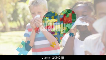 Image of colourful puzzle pieces heart over children blowing their noses Stock Photo