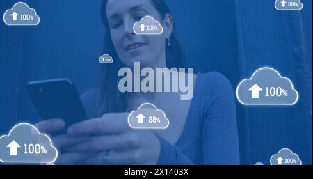 Image of digital clouds with percent going up over woman using smartphone Stock Photo