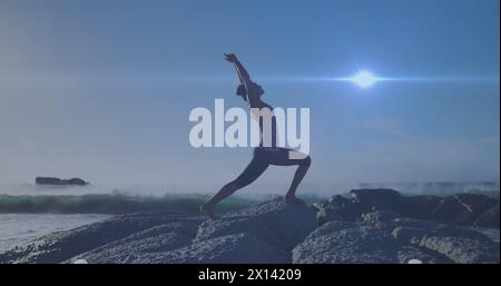Image of lights over caucasian woman practicing yoga on beach Stock Photo