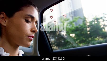 Multiple red heart icons floating against close up of caucasian woman smiling in the car Stock Photo