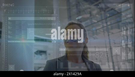 Image of data processing on screens over smiling caucasian businesswoman in modern building Stock Photo