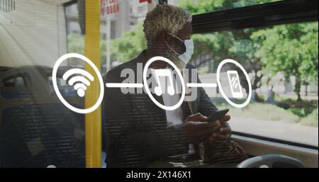 Image of application icons over senior african american man wearing mask and using cellphone Stock Photo
