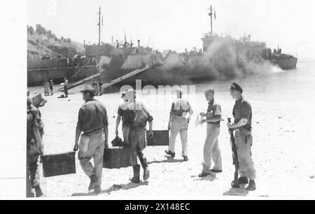 COMMANDOS RAID ALBANIA - General view of the beach. In the foreground, German prisoners carry boxes of medical supplies towards the waiting LCIs in the background British Army Stock Photo