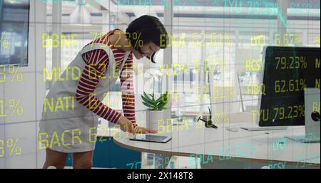 Composite of financial data processing over businesswoman using computer in office Stock Photo
