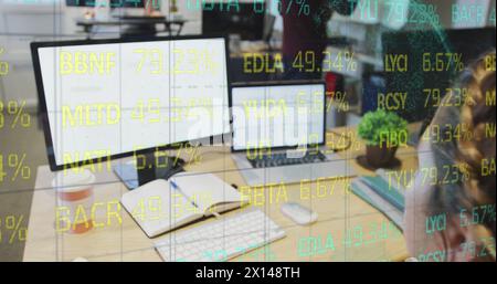 Composite of financial data processing over businesswoman using computer in office Stock Photo