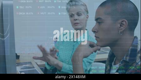 Image of trading board, graph over diverse coworkers discussing reports over computer in office Stock Photo