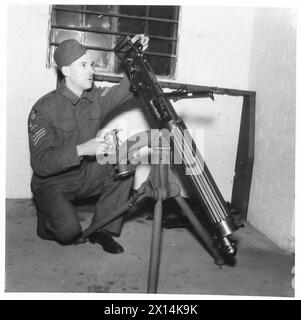 THE ACTIVITIES OF THE ROYAL ELECTRICAL AND MECHANICAL ENGINEERS - Armourer Staff Sergeant Wiltshire of Dronfield, Sheffield, was a fitter and is seen examining a Vickers machine gun in for repairs British Army Stock Photo