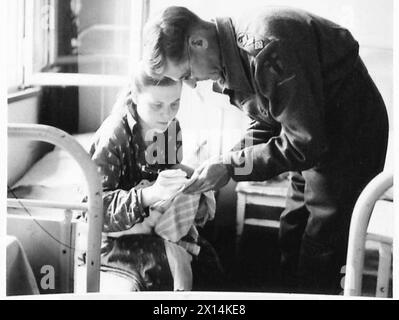 CHRISTENING BABIES IN BELSEN CAMP - Raissa Dorochova writes her name for the padre so he will get the spelling correct British Army, 21st Army Group Stock Photo