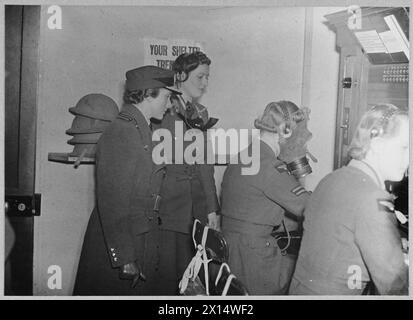 The Duchess of Gloucester visits a Coastal Command station and observes W.A.A.F. telephone operators using respirators to maintain RAF communications in gas attack conditions. Stock Photo