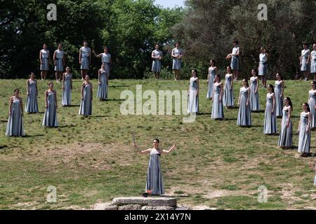 Ancient Olympia, Greece. 15th Apr, 2024. Greek actress Mary Mina (C), playing the role of the High Priestess, holds the flame during the final dress rehearsal of the Olympic flame lighting ceremony for the Paris 2024 Summer Olympic Games in Ancient Olympia, Greece, on April 15, 2024. Credit: Marios Lolos/Xinhua/Alamy Live News Stock Photo