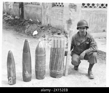 FIFTH ARMY : ANZIO BRIDGEHEAD COMPARISON IN GERMAN SHELLS - Four German shells that have been recovered on the bridgehead. Left to right: - 150 mm - 6 inch 180 mm - 7.2 inch 210 mm - 8.4 inch 280 mm - 11.2 inch 1st Sgt. William A. Hill of Charlestown, S.C., U.S.A. holds up a stick marked off in 6-inch lengths to give an idea of the size of the shells. The 280 mm shell has a mose-cap which is estimated to add 24' to its length. Round the body of the shell are raised strips which fit into the rifling of the gun barrel, the gas seal being obtained by a narrow copper band at the base end of the ra Stock Photo