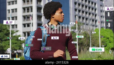 Image of changing numbers, icons over biracial man standing and looking at smartwatch Stock Photo