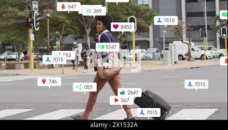 Image of multiple notification bars over african american woman crossing street with trolley bag Stock Photo