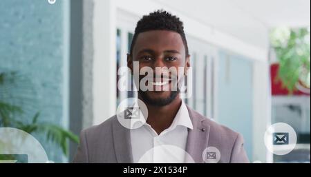 Image of envelope icon in circles over smiling african american man standing in office Stock Photo