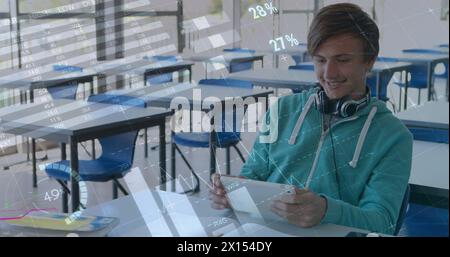 Image of digital interface with data, icons and charts moving over smiling male student using tablet Stock Photo